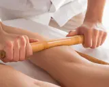 Relaksacyjny masaż pałeczkami bambusowymi na nogach. Terapeuta wykonuje głęboki masaż, przynoszący ulgę i odprężenie.