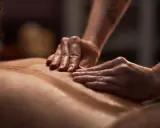 Dłonie terapeuty wykonują relaksujący masaż pleców, ukazując różne rodzaje masażu.
