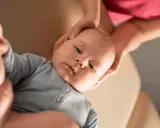 Delikatne dłonie osteopaty pediatrycznego obejmują główkę niemowlęcia, zapewniając mu komfort i wsparcie podczas terapii.