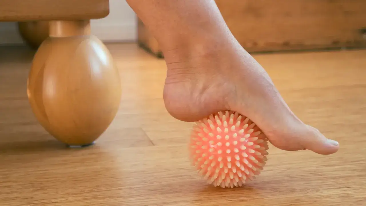 Stopa masowana kolczastą piłką sensoryczną, element rehabilitacji stopy.